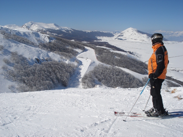 Skier in orange and black jacket looking over the ski slopes in Abruzzo